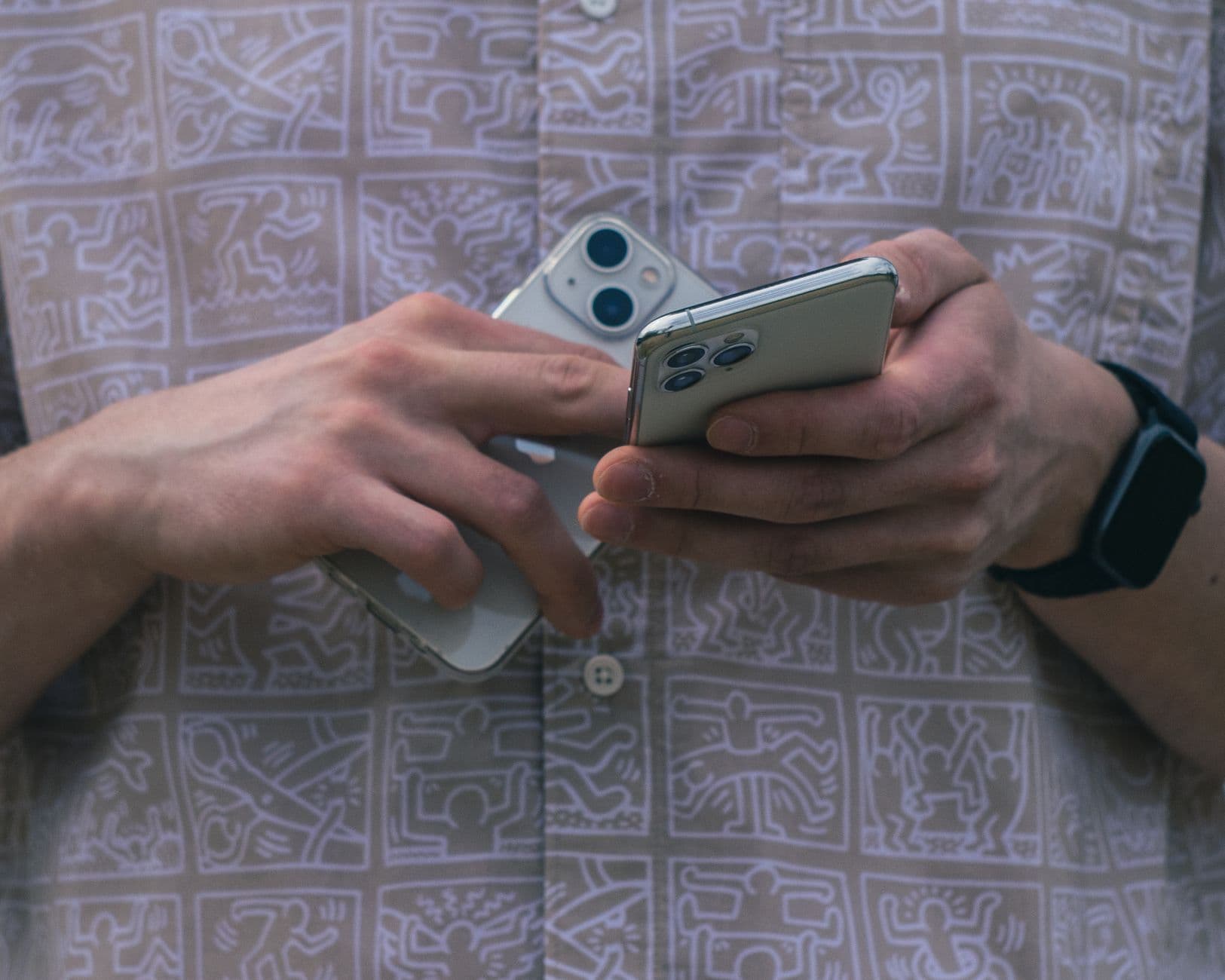 Hands holding two smartphones to compare booking platforms