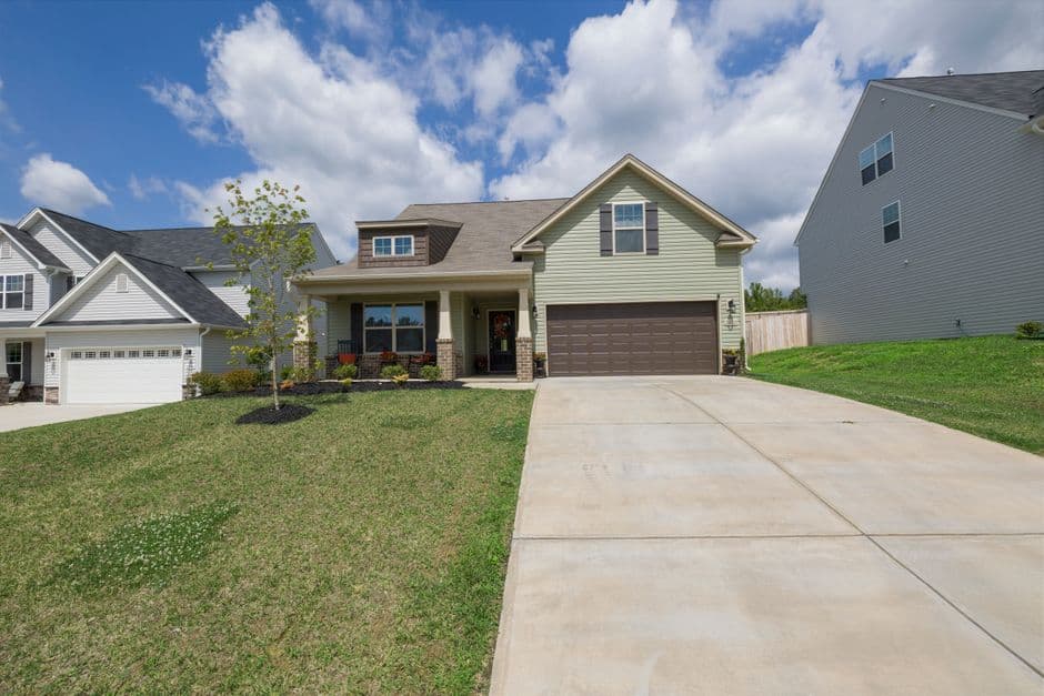 A modern suburban detached house with a spacious driveway under a bright blue sky