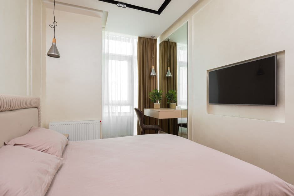 Comfortable compact bedroom with a soft bed, mirror, and small window in a modern home