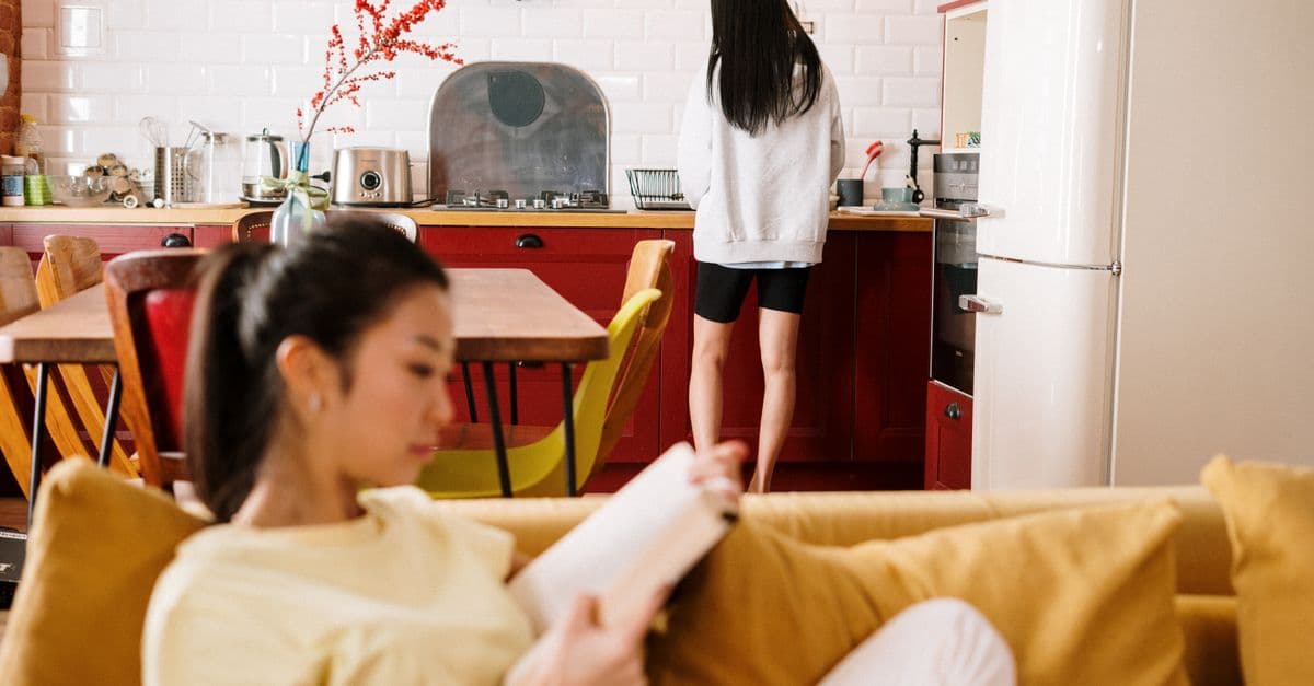 거실 소파에서 책을 읽는 사람과 주방에 있는 사람 — 한 집을 나눠 쓰는 셰어하우스의 일상