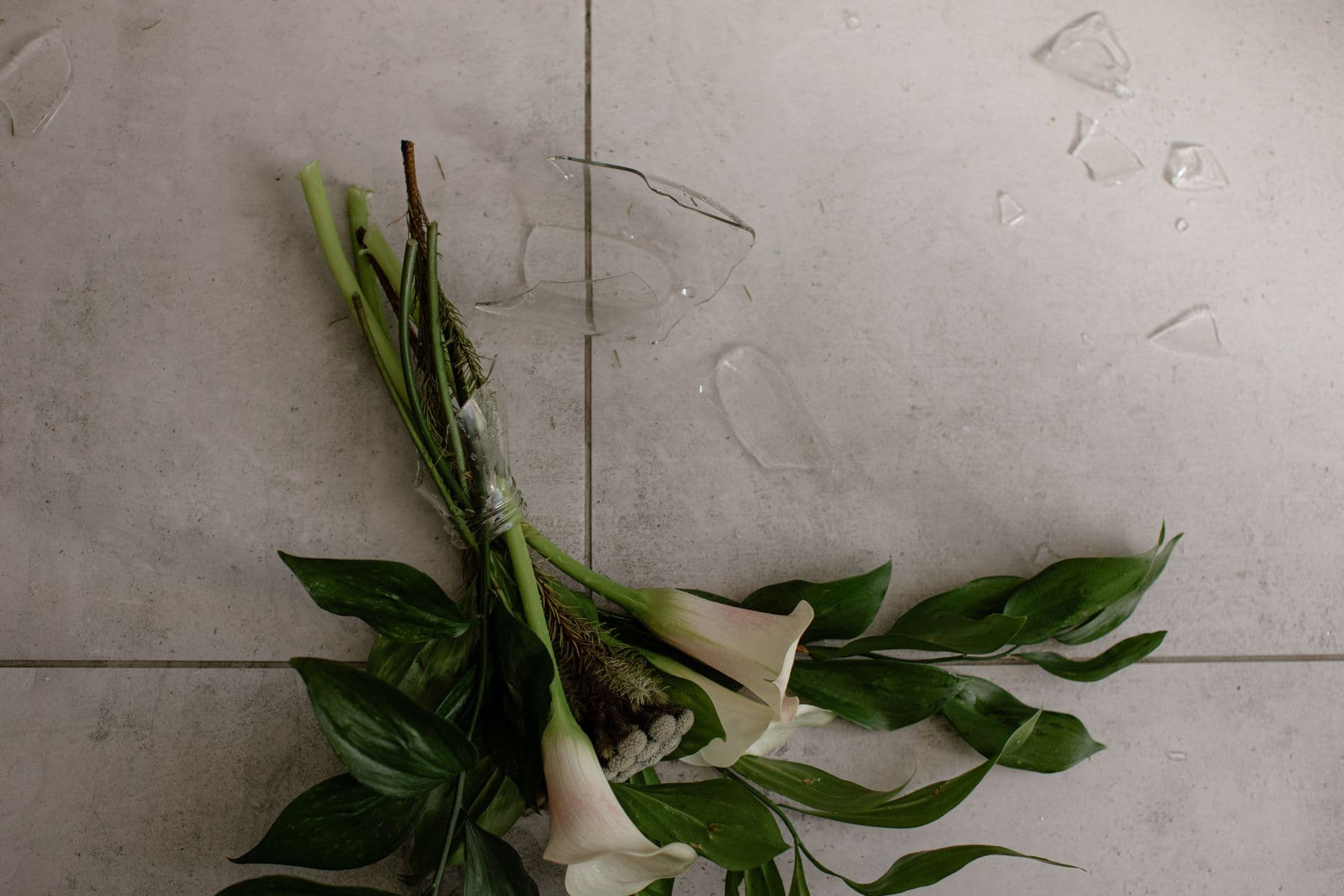 A broken vase and scattered flowers on the floor after guest damage
