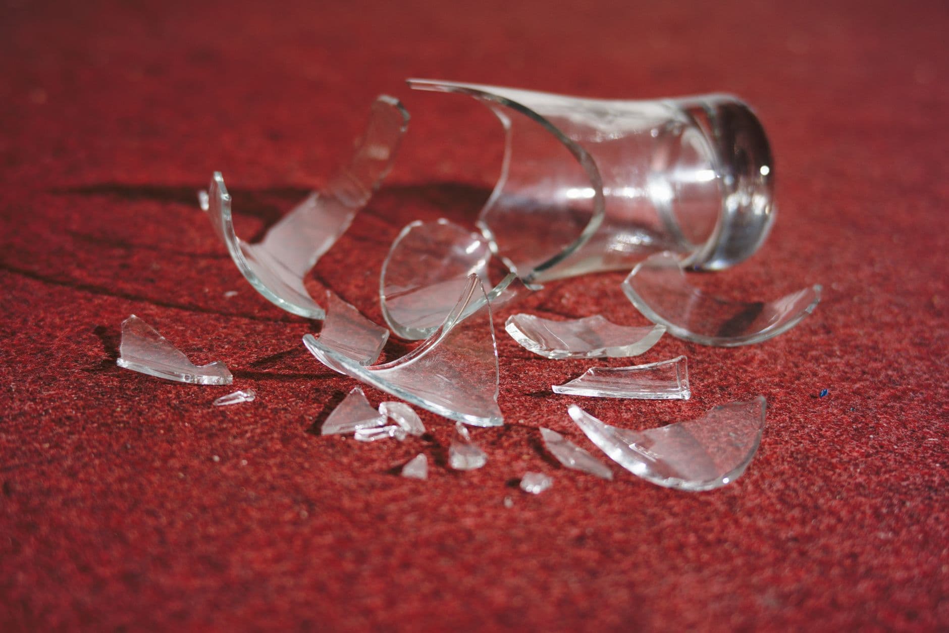 Broken glass scattered on a red carpet