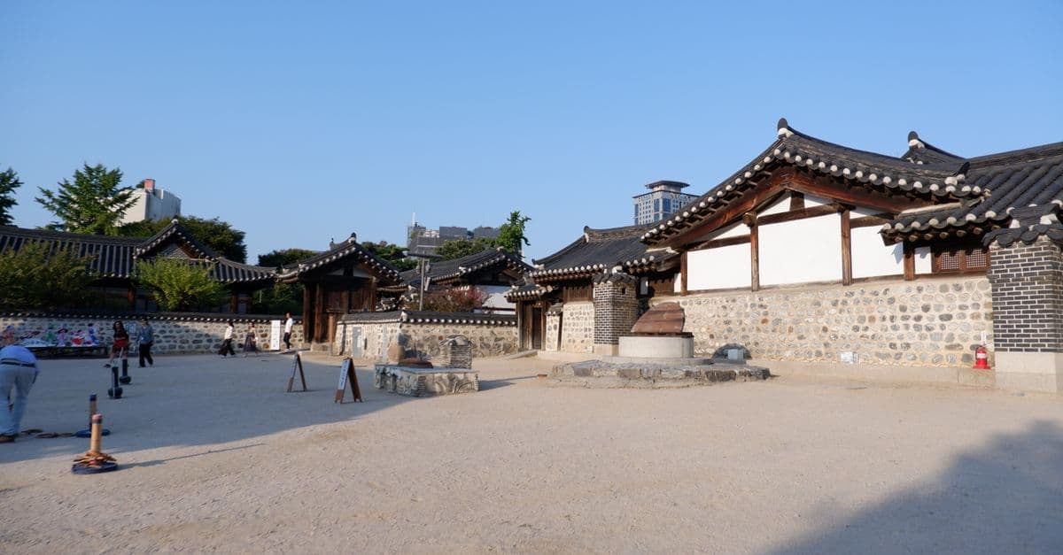 도심 빌딩을 배경으로 기와지붕이 이어진 한옥마을 풍경