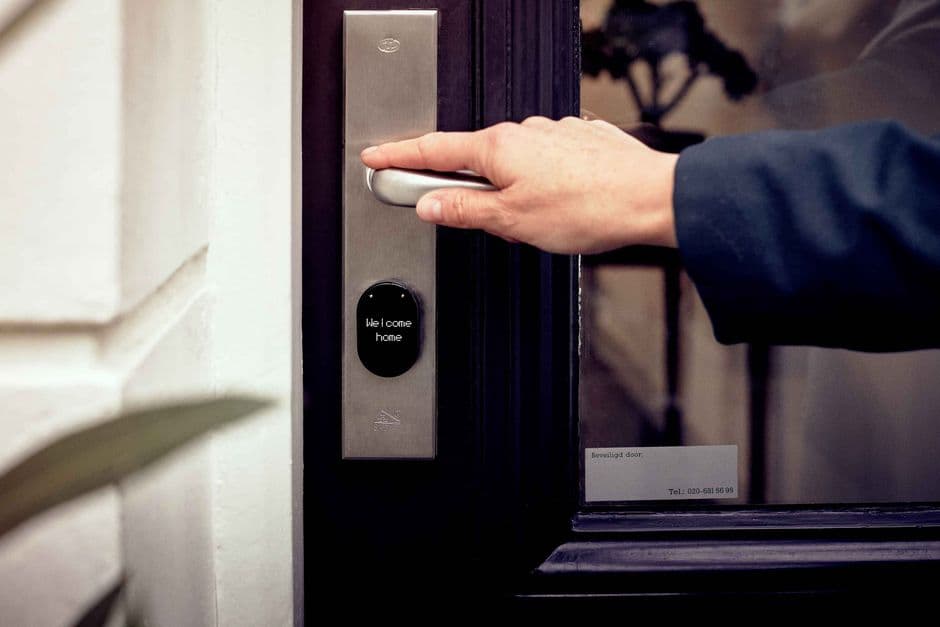 A hand opening a smart home door with a digital access panel